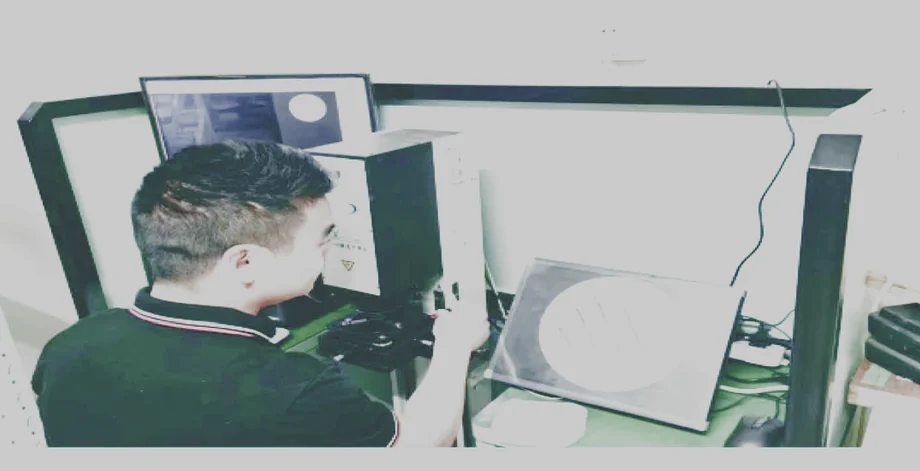 Operator inspecting optical parts with magnification equipment